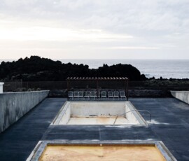 An empty pool with chairs near the cliff and a sea